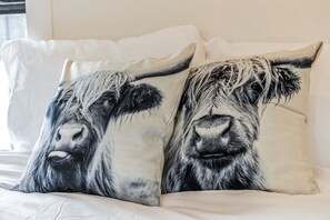 Een bed met twee kussens, voorzien van een zwart-wit koeienpatroon.