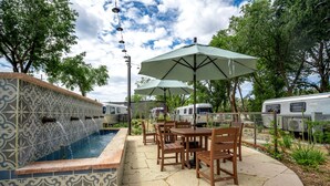 Ein Pool mit einer Kachelwand, Sitzgelegenheiten im Freien und einem Zaun.