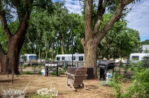 A campsite with RVs, a grill, and a bench.