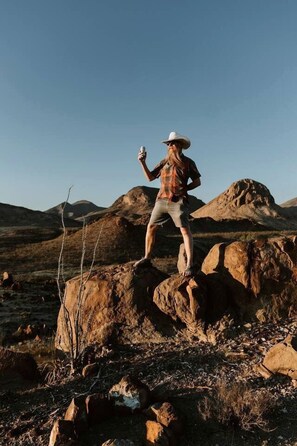 A person standing on a rock in a natural landscape with mountains in the background. - Unique and Pet Friendly Glamping Dome with Views of Big Bend National Park, Perfect for a Texas Glamping Getaway (Terlingua)
