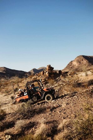 Un véhicule évoluant dans un environnement naturel accidenté, caractérisé par un terrain rocheux et une végétation clairsemée.