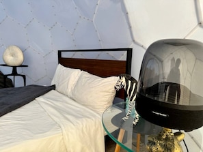 A modern bedroom with a glass table, a zebra sculpture, and a unique geometric wall design. - Unique and Pet Friendly Glamping Dome with Views of Big Bend National Park, Perfect for a Texas Glamping Getaway (Terlingua)