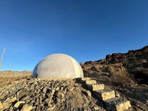 A dome-shaped structure with a hexagonal pattern, surrounded by rocky terrain and sparse vegetation.