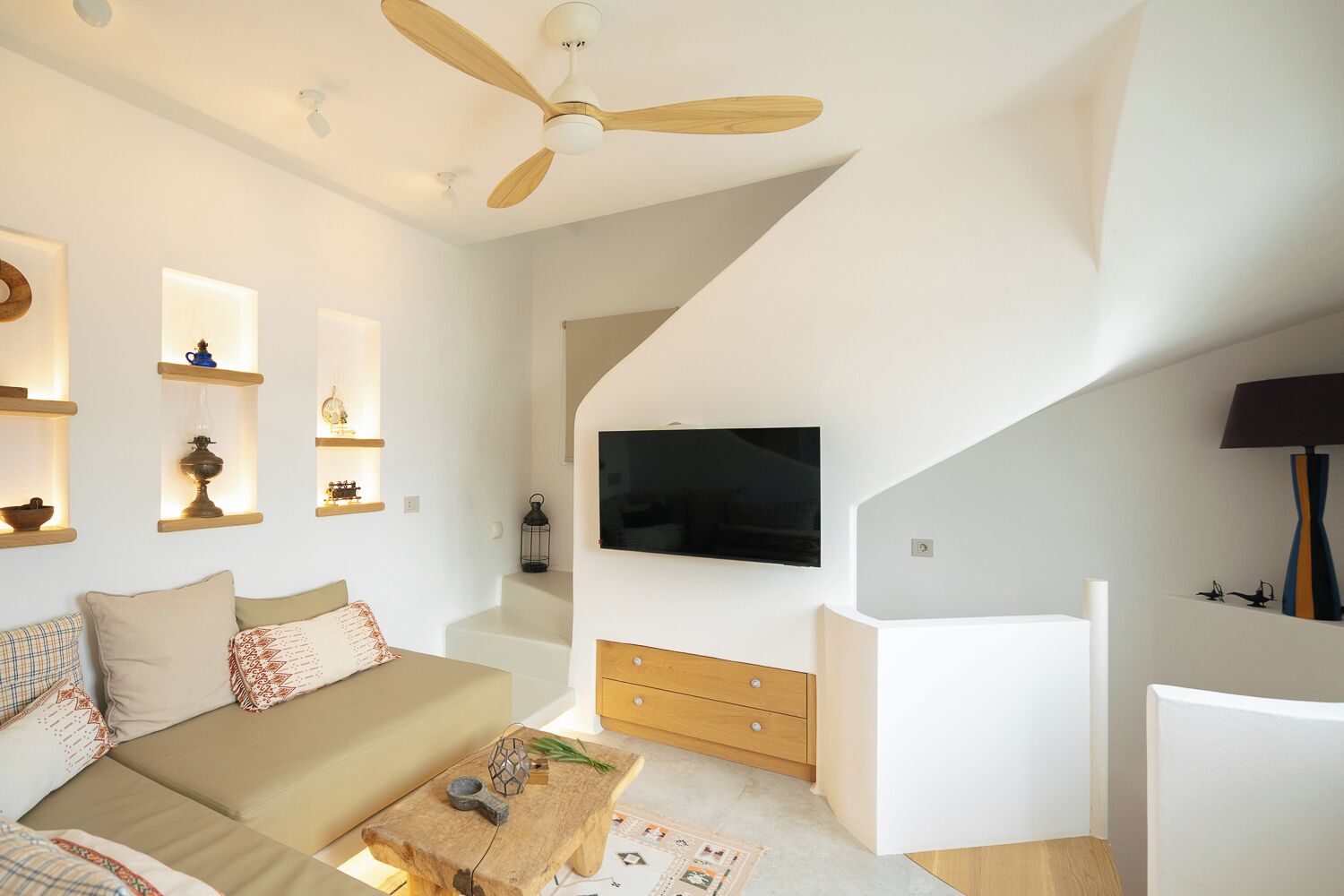 Ein modernes Wohnzimmer mit einer Couch, einem Couchtisch, einem Fernseher und einem Deckenventilator.