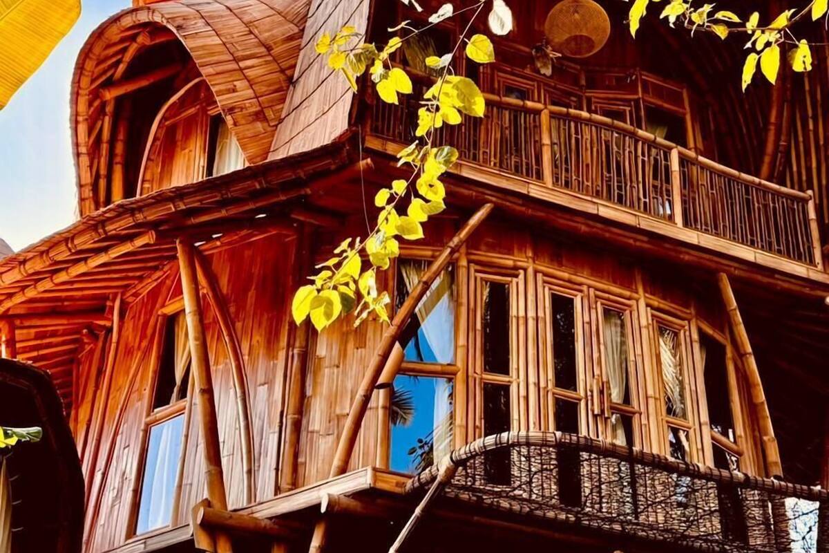 Una estructura de madera de varios niveles con balcones y ventanas, rodeada de vegetación.