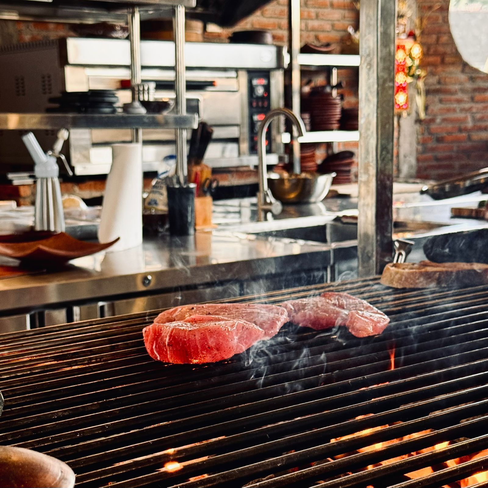 A kitchen with a grill, cooking meat, and various kitchen utensils.