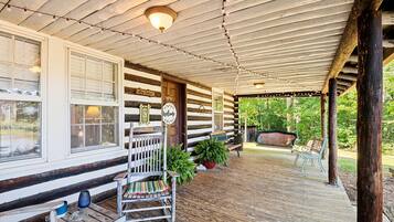 A log cabin with a porch, wooden benches, a welcome sign, and a dog cabin sign.