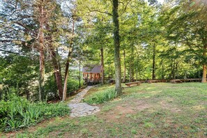Un rustico chalet con un vialetto in pietra che vi conduce, immerso in una fitta foresta.