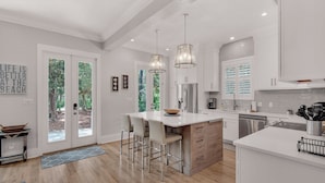 A modern kitchen with white cabinetry, stainless steel appliances, and a large island with bar stools. - 3BR Retreat in Grove by the Sea + Free Tickets: Dolphin Cruise & More! (Santa Rosa Beach)
