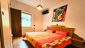 A bedroom with a wooden bed, a window with a view, a ceiling fan, and a painting on the wall. - Apartment Gerda (Pappenheim)