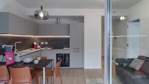 Una cocina moderna con comedor, sofá y separador de vidrio.