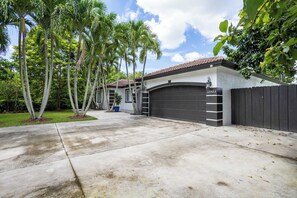 Une propriété résidentielle dotée d’un garage, d’une allée et d’une pelouse bien entretenue agrémentée de palmiers.