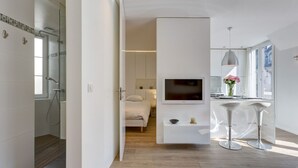 A modern hotel room with a shower, a bed, a TV, and a dining area with bar stools. - CHAMPS ELYSEES APARTMENT (Paris)