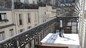 A balcony with a table set for two, a bottle, and a glass. - CHAMPS ELYSEES APARTMENT (Paris)