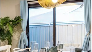 A dining area with a table set for four, white chairs, and a hanging light fixture. - A Sunday Kind of Stay -  Home Near Manly + Shops (Capalaba)