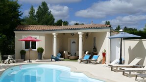 Une piscine avec des chaises longues et un espace patio couvert.