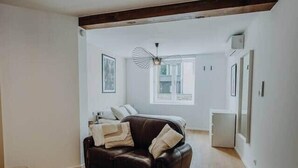 A spacious living room with a brown leather sofa, a wooden floor, and a ceiling fan. - Loft d'Houffalize - by Mansio (Houffalize)