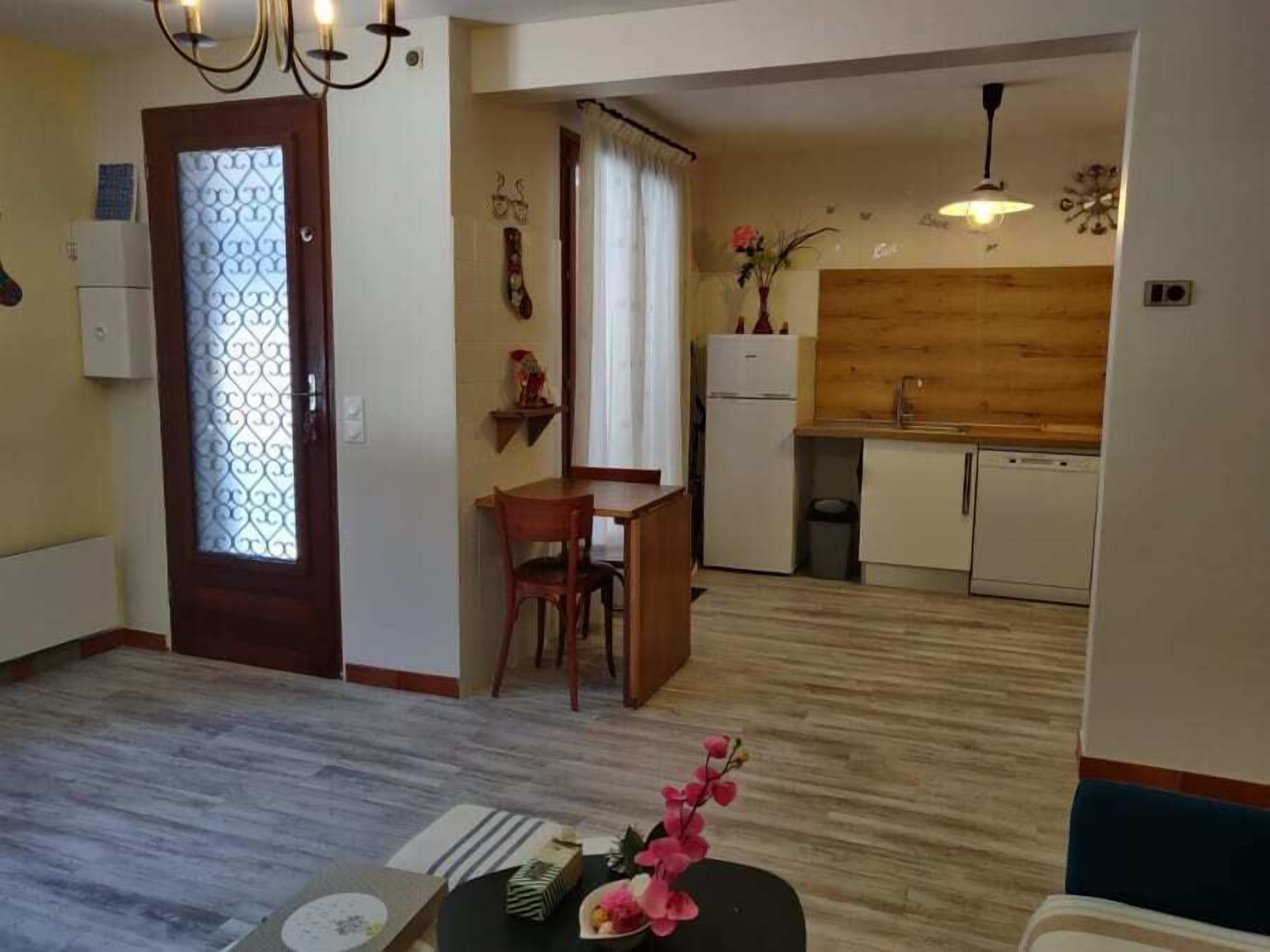 A compact living space with a dining area, kitchenette, and a wooden accent wall.