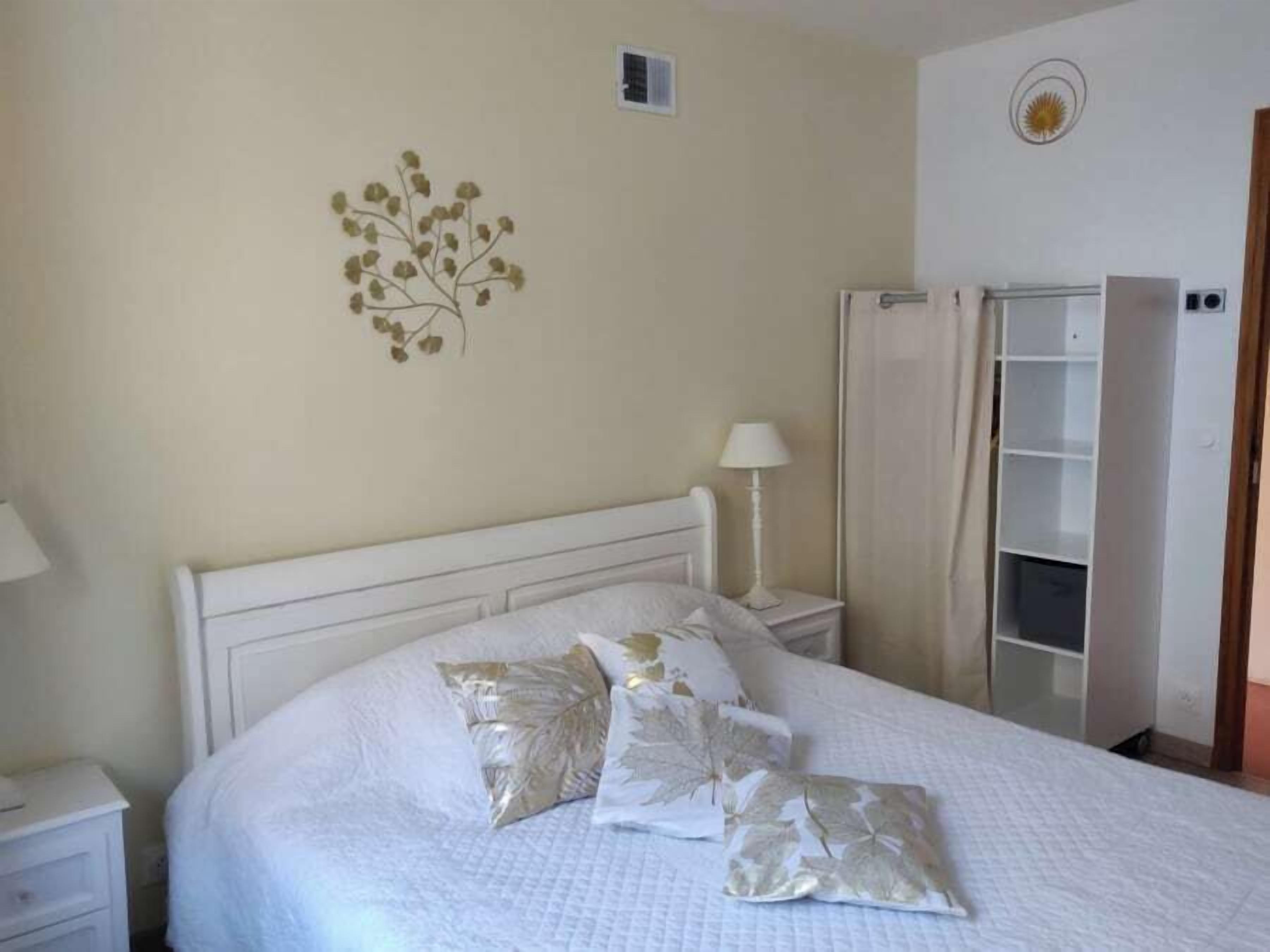 Une chambre à coucher comprenant un lit, une table de chevet, une lampe, une armoire et un élément de décoration murale.