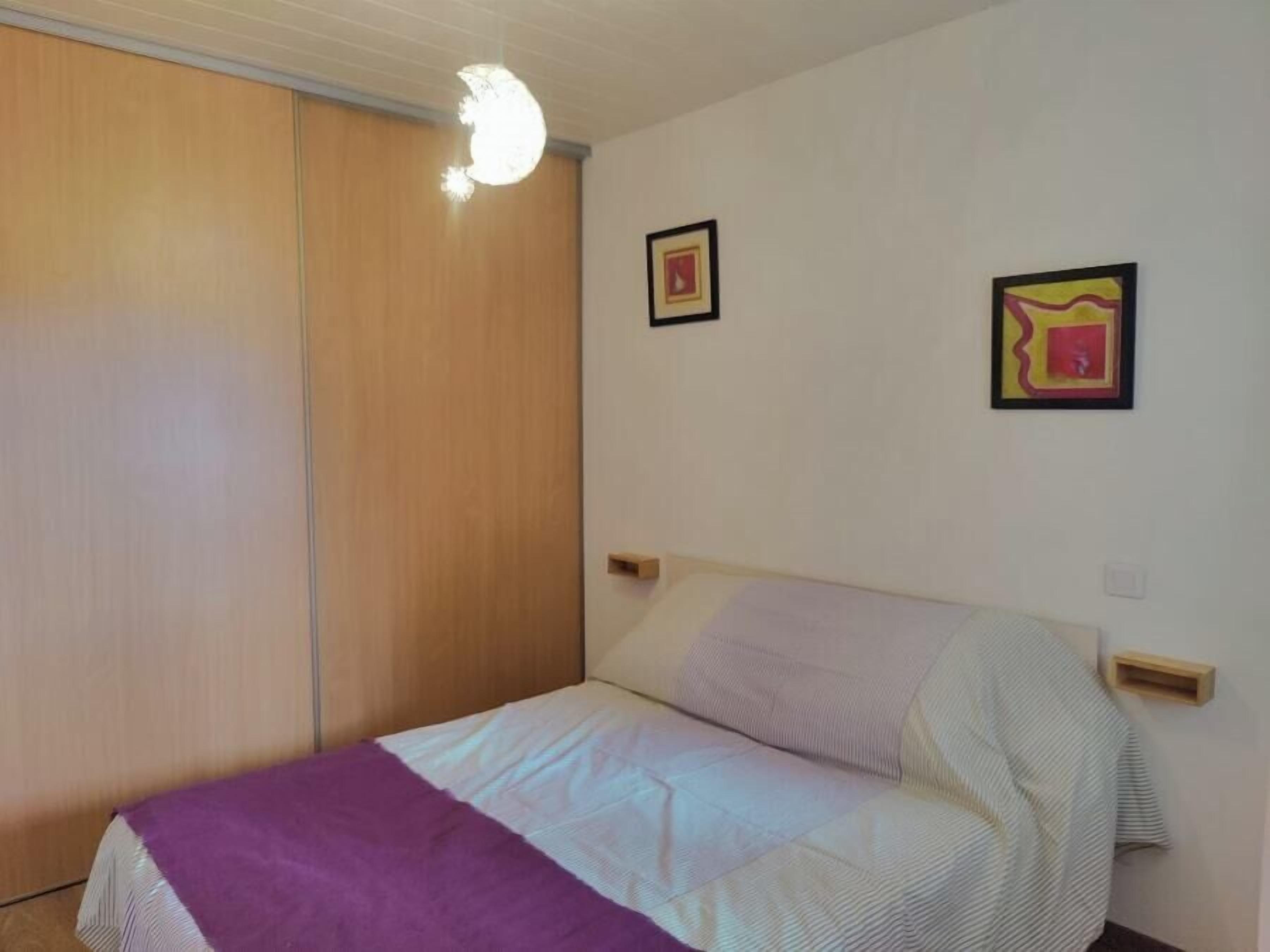 Un dormitorio con una cama, un armario de madera y dos cuadros en la pared.