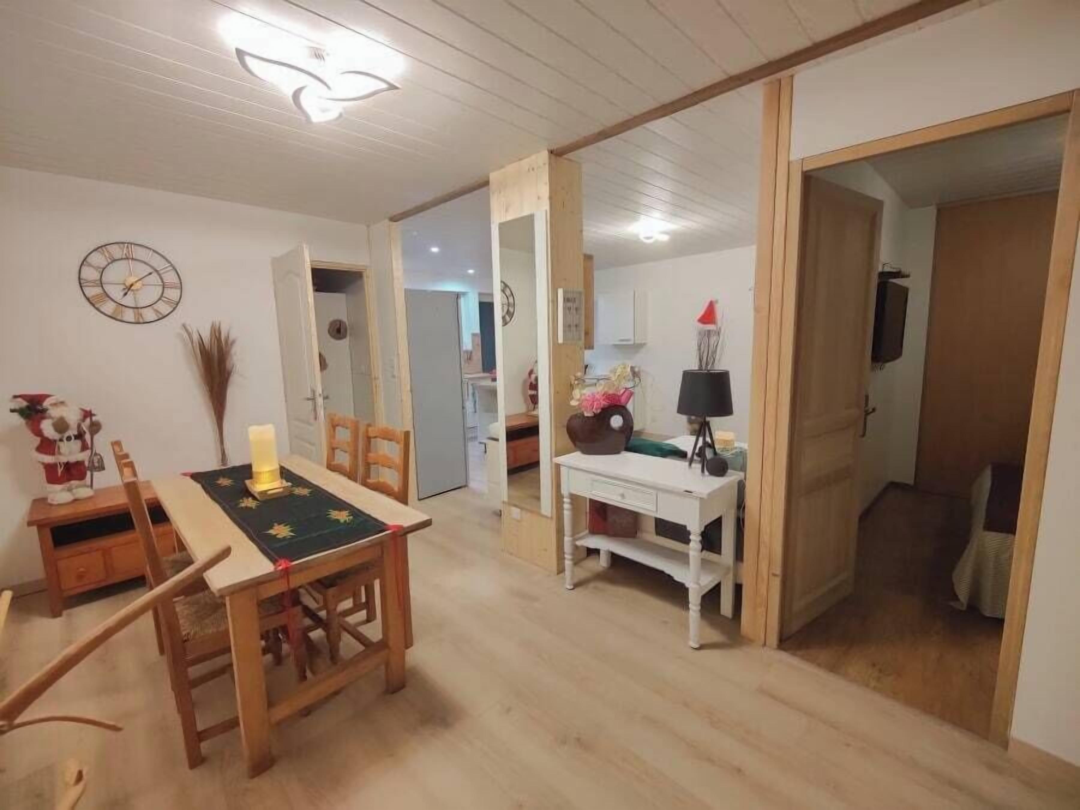 Un comedor con una mesa y sillas de madera, un escritorio blanco con una lámpara y un reloj en la pared.