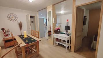 Un comedor con una mesa y sillas de madera, un escritorio blanco con una lámpara y un reloj en la pared.