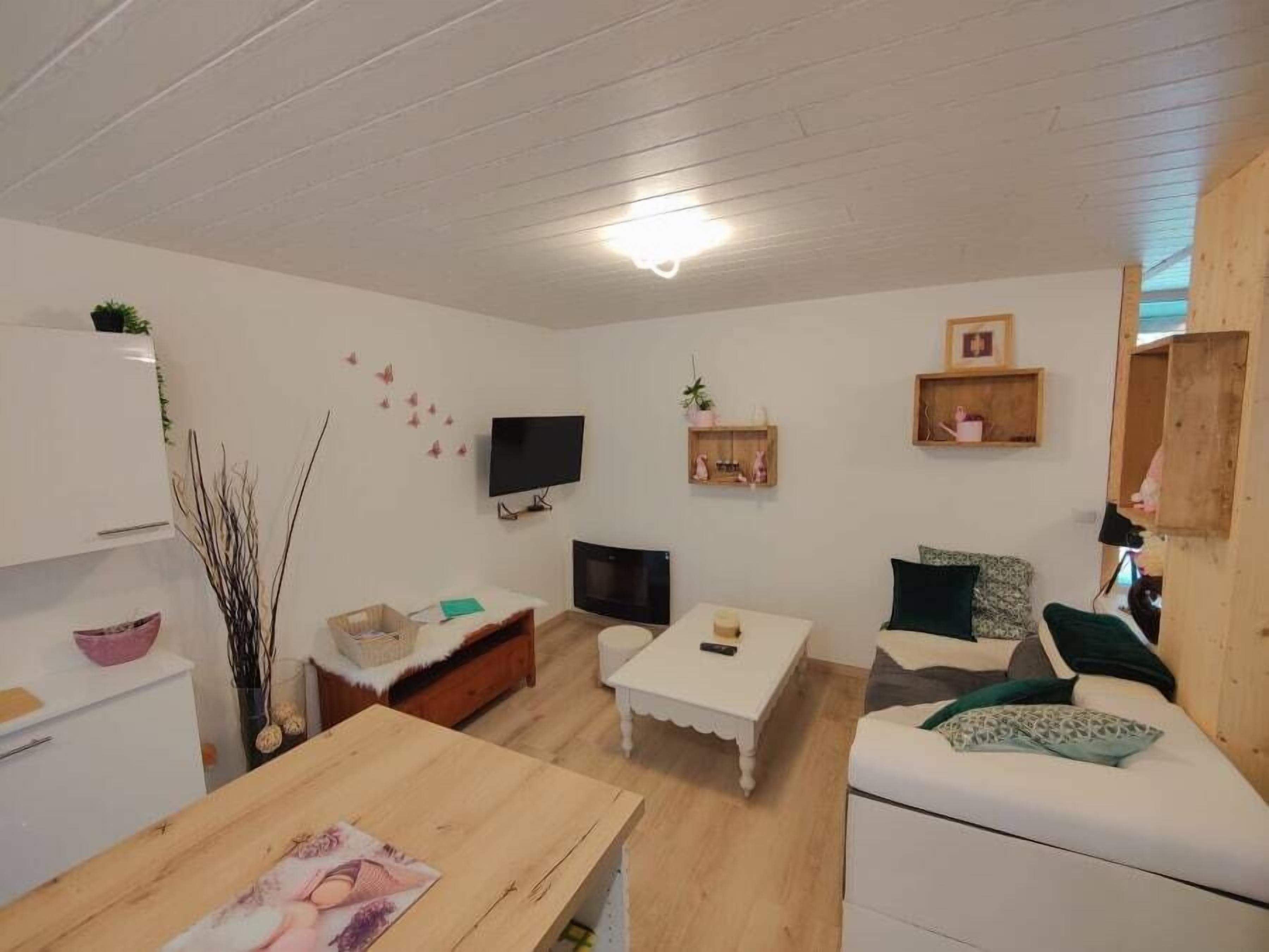 A modern living room with a white sofa, a wooden coffee table, a TV, and a fireplace.