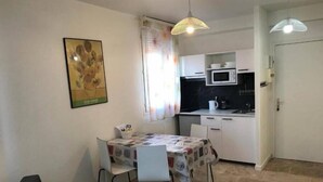 Egy kompakt, multifunkciós lakótér, amelyben étkező, kis konyhasarok található, és egy ajtón át egy másik helyiségbe lehet jutni.