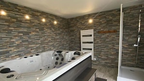 Une salle de bain moderne avec un mur au motif de pierre, une grande baignoire et une cabine de douche en verre.