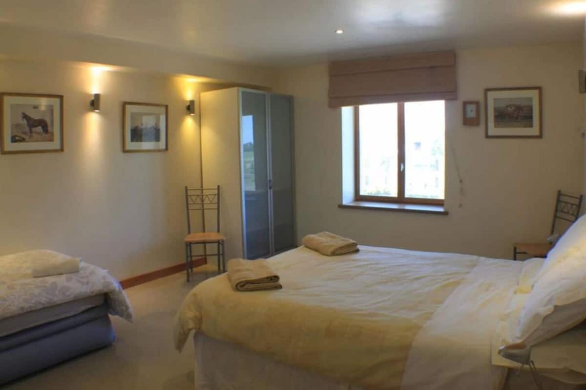 A bedroom with a bed, a chair, a wardrobe, and a window.