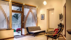 Ein modernes Interieur mit einer Couch, zwei Sessel, einem kleinen Tisch und einem Fernseher an der Wand.
