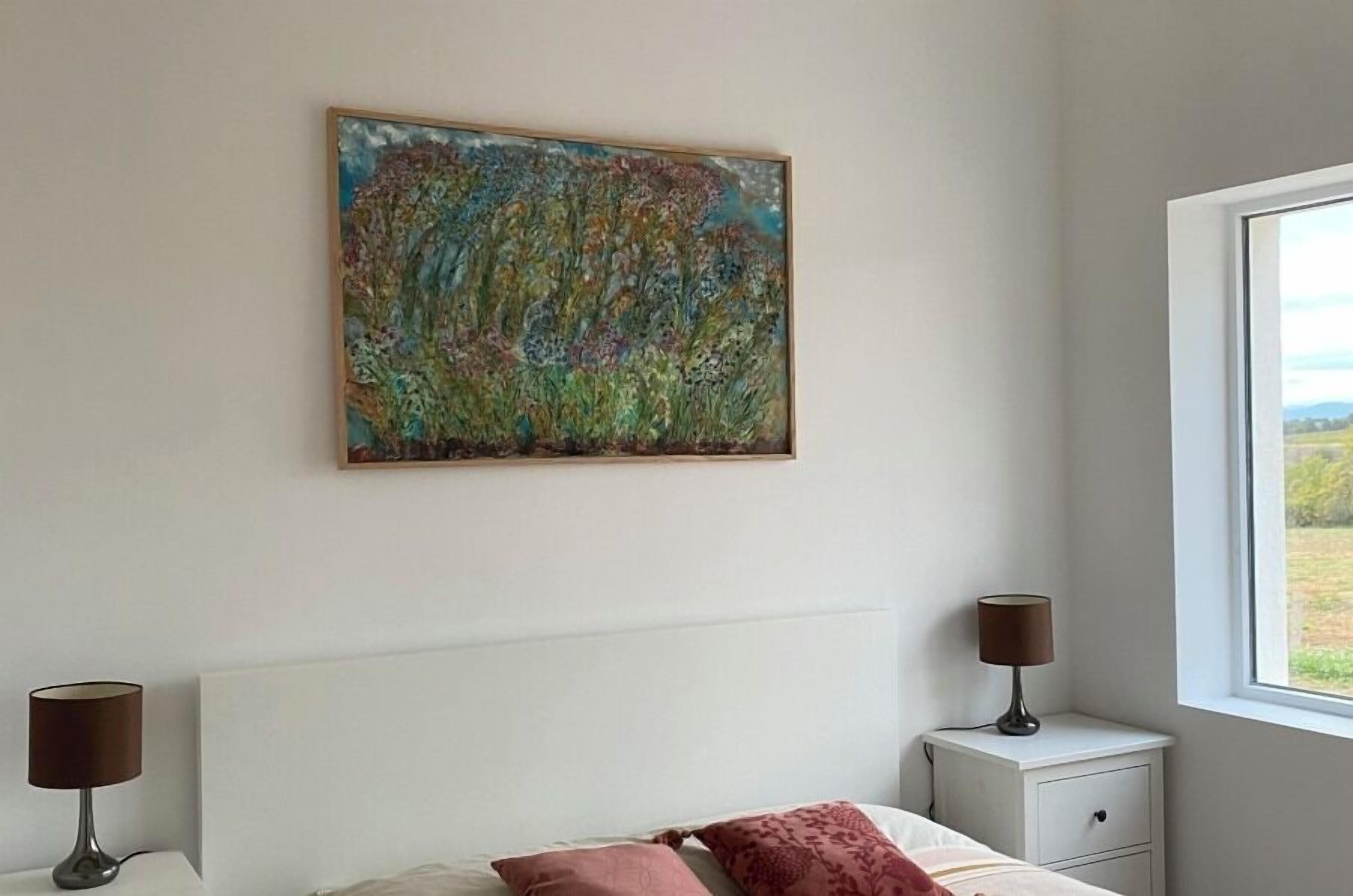 Een slaapkamer met een bed, nachtlampjes, een nachtkastje en een raam met uitzicht.
