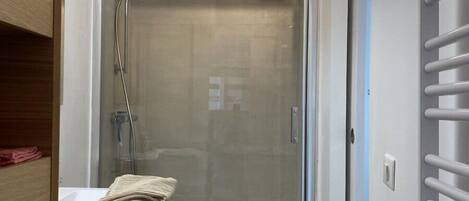 A modern bathroom with a glass-enclosed shower, a white sink, and a towel rack.