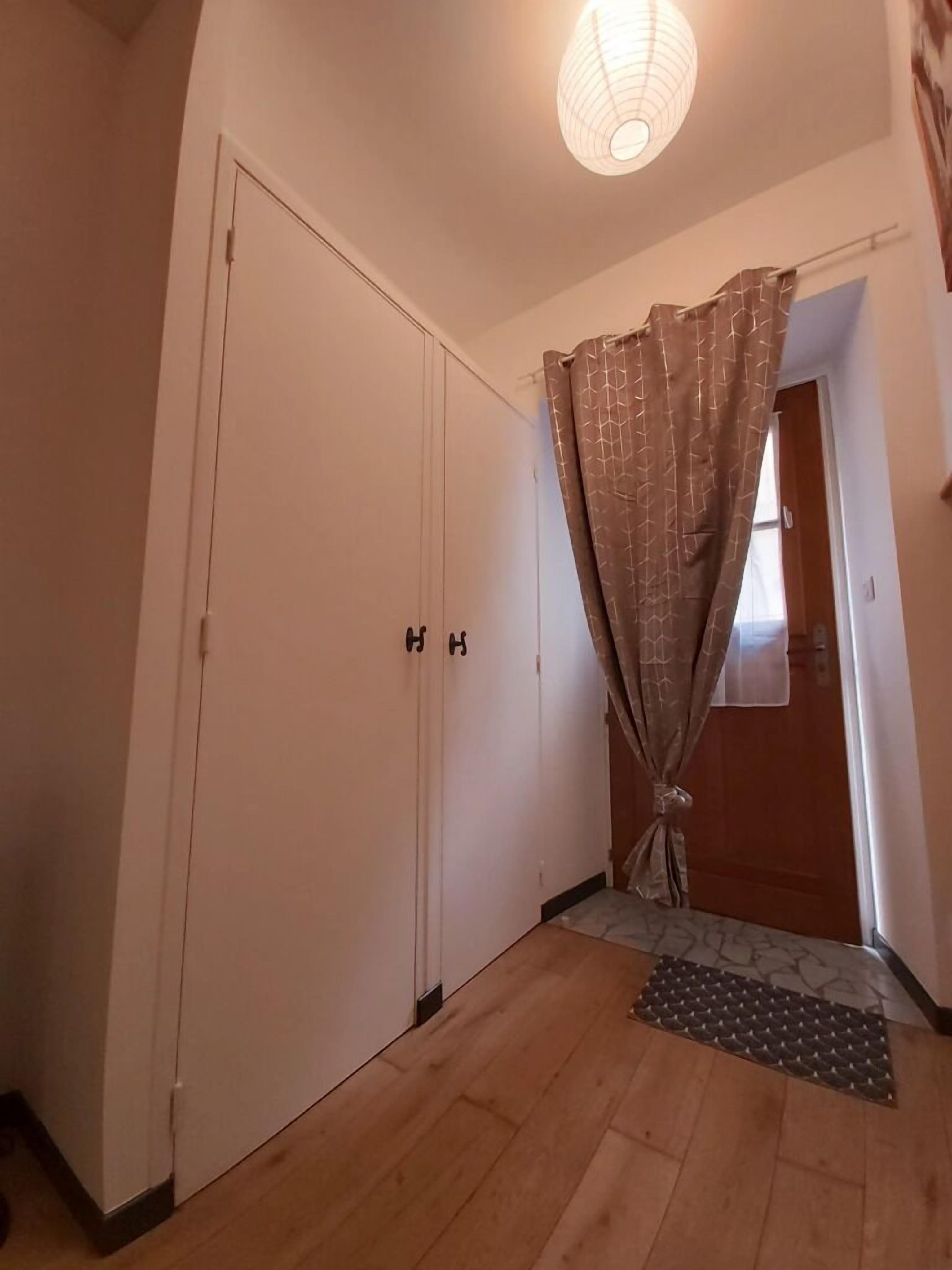 A hallway with a wooden floor, a white door, and a curtain.