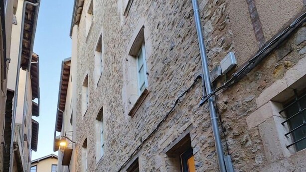A narrow cobblestone street flanked by old stone buildings with blue shutters and a visible utility pole. - Le Saint-Georges (Villefranche-de-Rouergue)