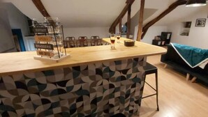 A cozy kitchen with a wooden island, a hanging light fixture, and a dining area with chairs. - Le Saint-Georges (Villefranche-de-Rouergue)