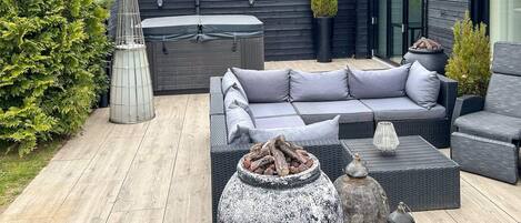 A patio with a sofa, a large vase, and a lantern.