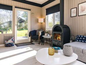 A cozy living room with a fireplace, a sofa, a coffee table, and a view of the outdoors.