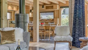 A cozy wooden interior with a dining area, a fireplace, and a comfortable seating arrangement.