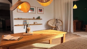 Ein gemütliches Wohnzimmer mit Couchtisch aus Holz, Hängeleuchten aus Weidwerk und einem bequemen Sessel.