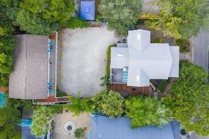 An aerial view of a building with a large central courtyard, surrounded by trees and a parking area.