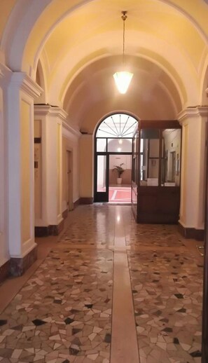 A hallway with a tiled floor, arched ceiling, and a light fixture.