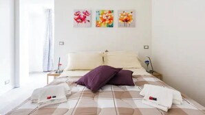 A hotel room with a bed, pillows, a nightstand, and three wall-mounted flower paintings. - Sixty one luxury room Apartment 100 sqm.,central, in prestigious area. (Roma)