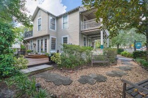 A two-story house with a porch, a deck, and a garden with stepping stones.