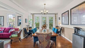 A dining area with a wooden table, blue chairs, and a chandelier.