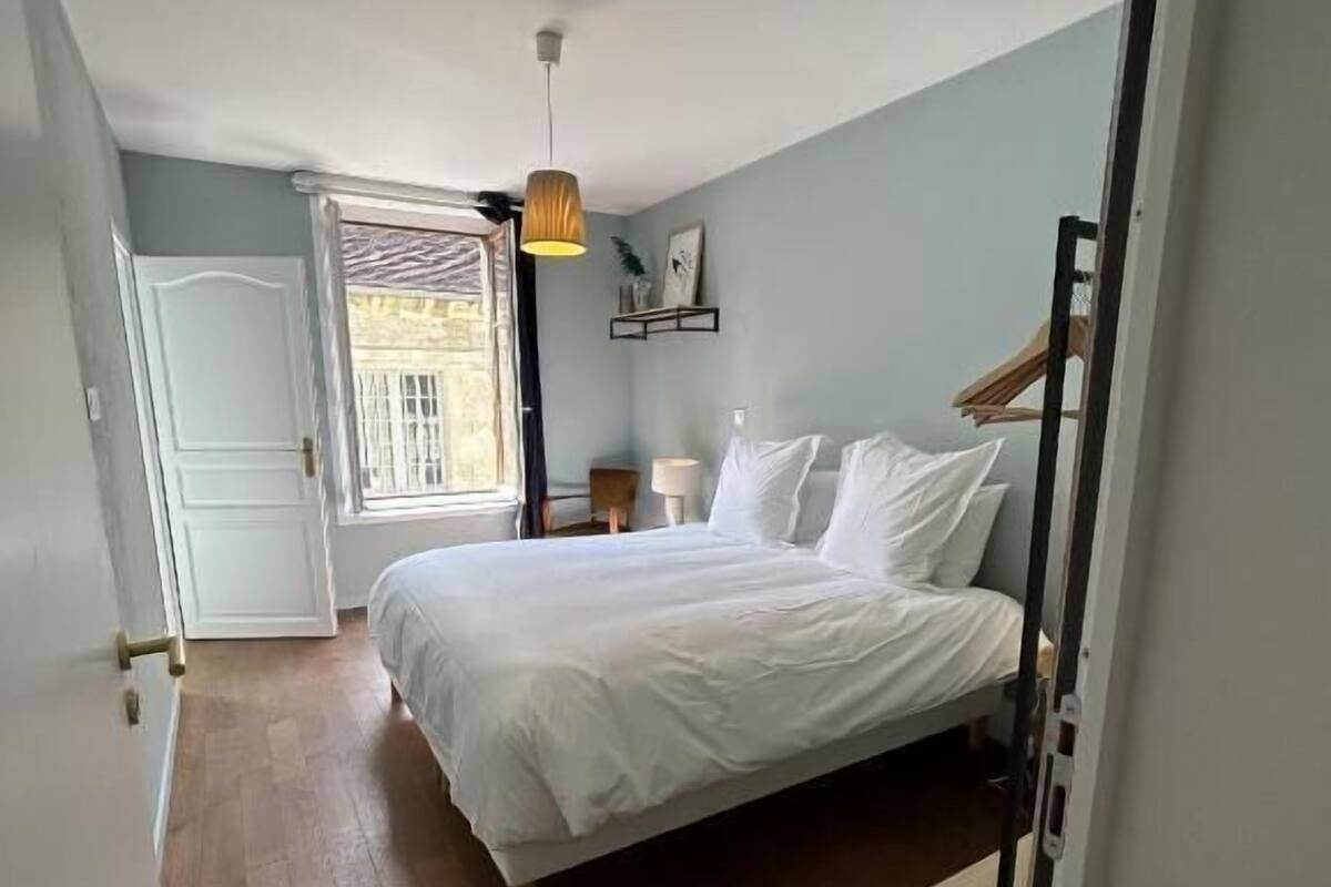 Ein Schlafzimmer mit Bett, Nachttisch, Lampe und Fenster.