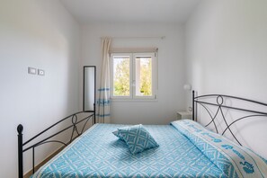 Ein Schlafzimmer mit Bett, Fenster, Nachttisch und Spiegel.