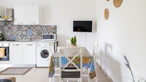 Een kleine keuken met een wasmachine, magnetron en een flatscreen televisie aan de wand.