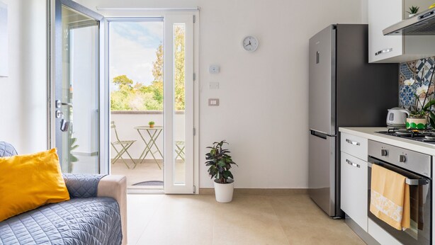 Een moderne keuken met een koelkast, oven en een klok aan de muur.