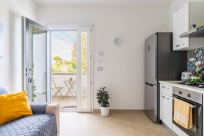 Een moderne keuken met een koelkast, oven en een klok aan de muur.